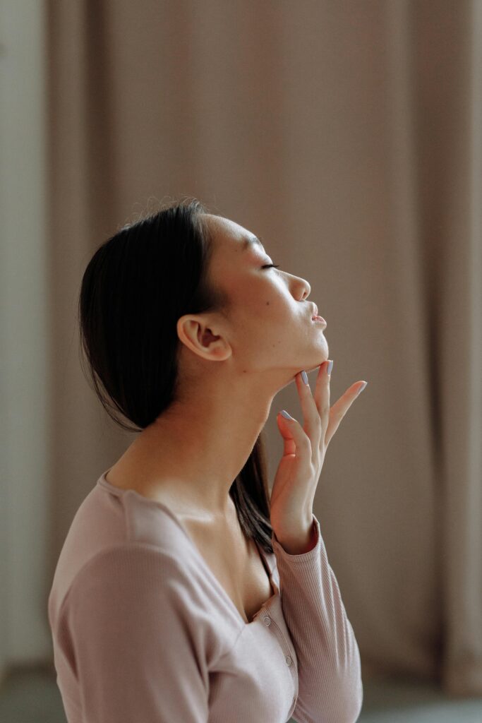 Woman touching her face, enjoying results of contouring for reducing double chin and defining jawline
